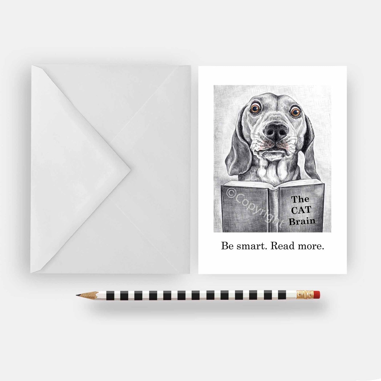 Greeting card featuring a wax pastel drawing of a dachshund dog reading a book about cats. Black and white with a hint of colour. By Deidre Wicks