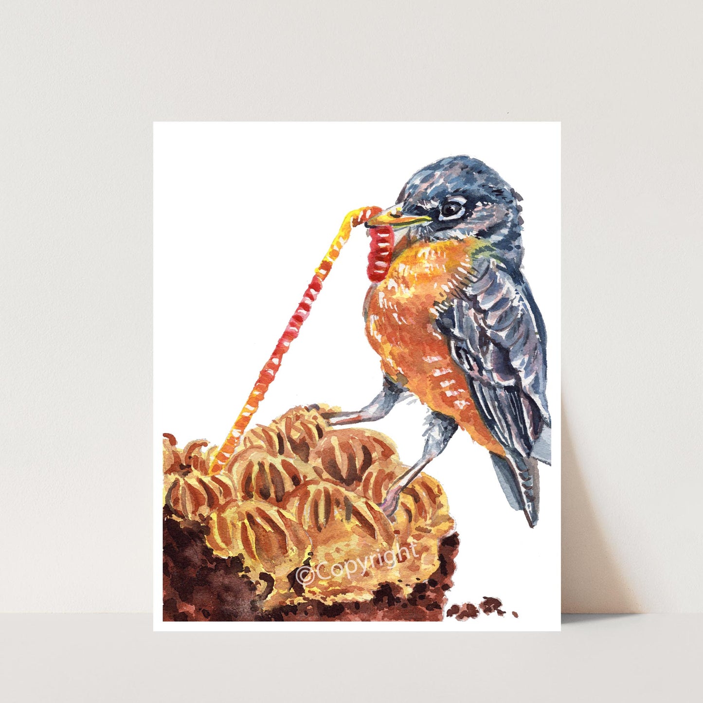 Watercolour painting of a robin pulling a gummy worm from a piece of cake