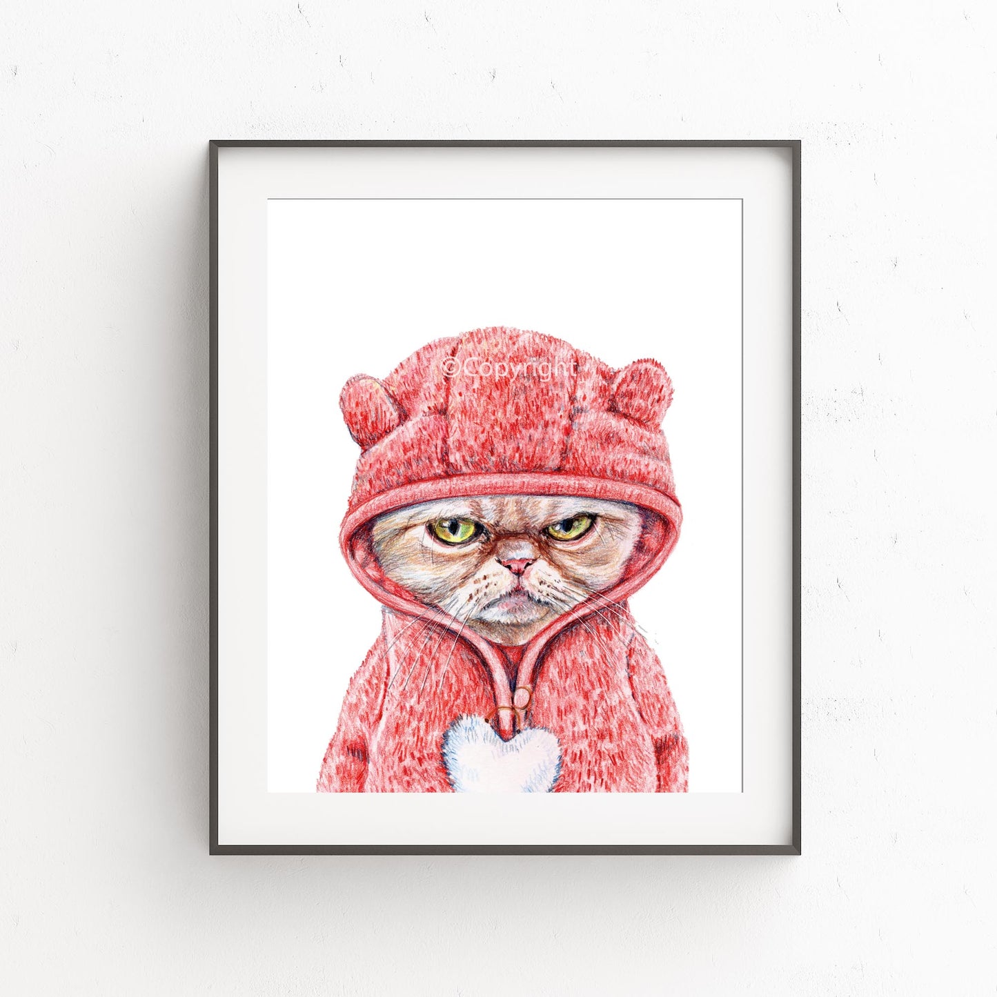 Framed artwork of a cat in a pink hood with bear ears on a white background
