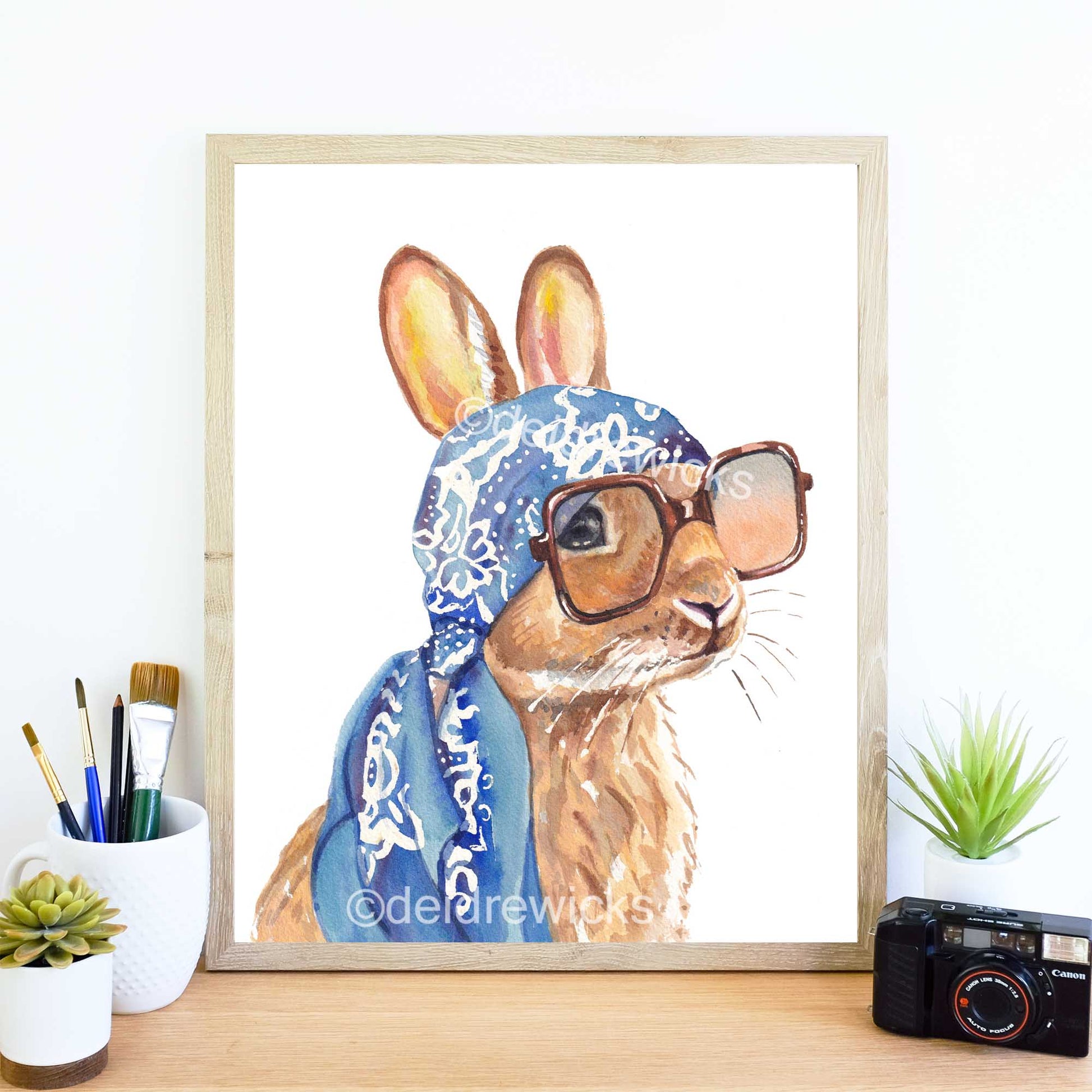Framed example of a watercolour painting of a brown bunny rabbit wearing a vintage scarf and big sunglasses. Vacation time! Art by Deidre Wicks