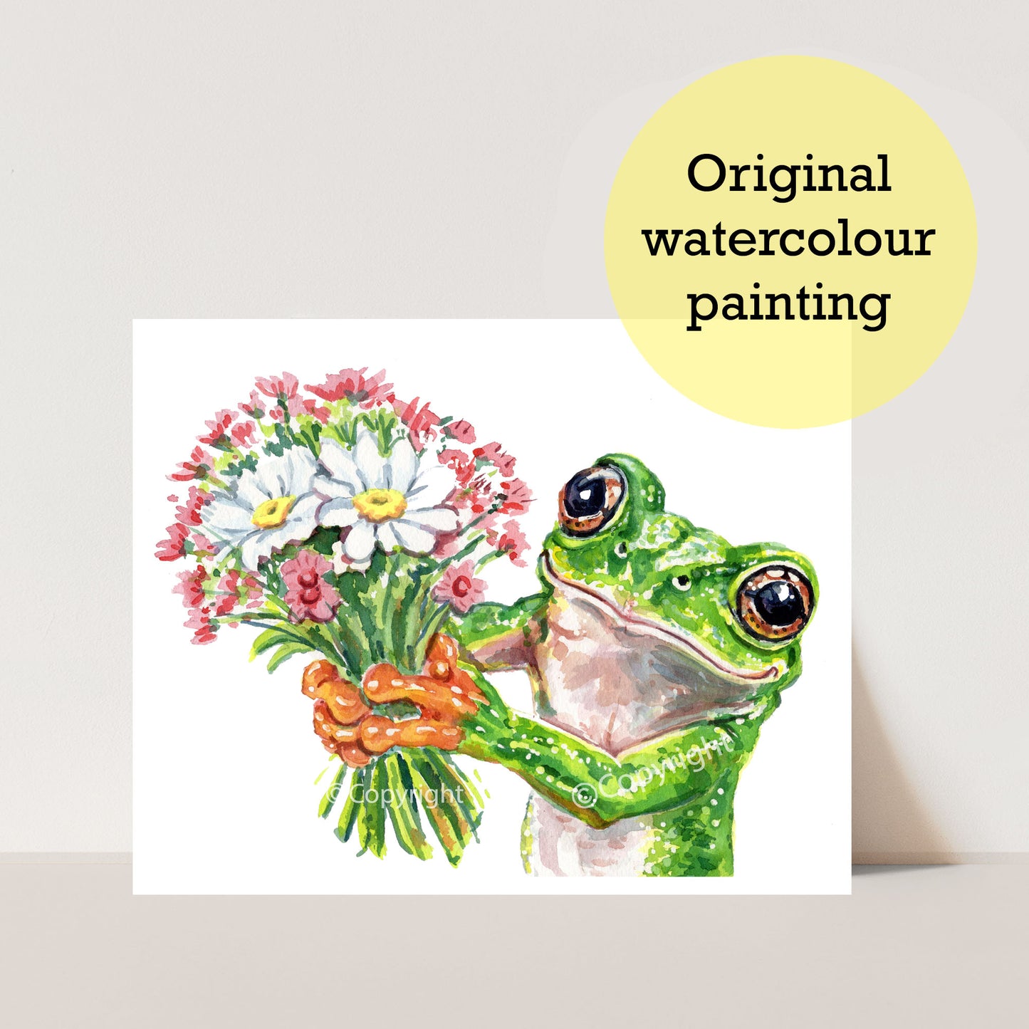 A watercolour painting of a green tree frog holding a bouquet of white and pink flowers, displayed on a white card against a light beige background with a yellow circular badge that reads 'Original watercolour painting'.