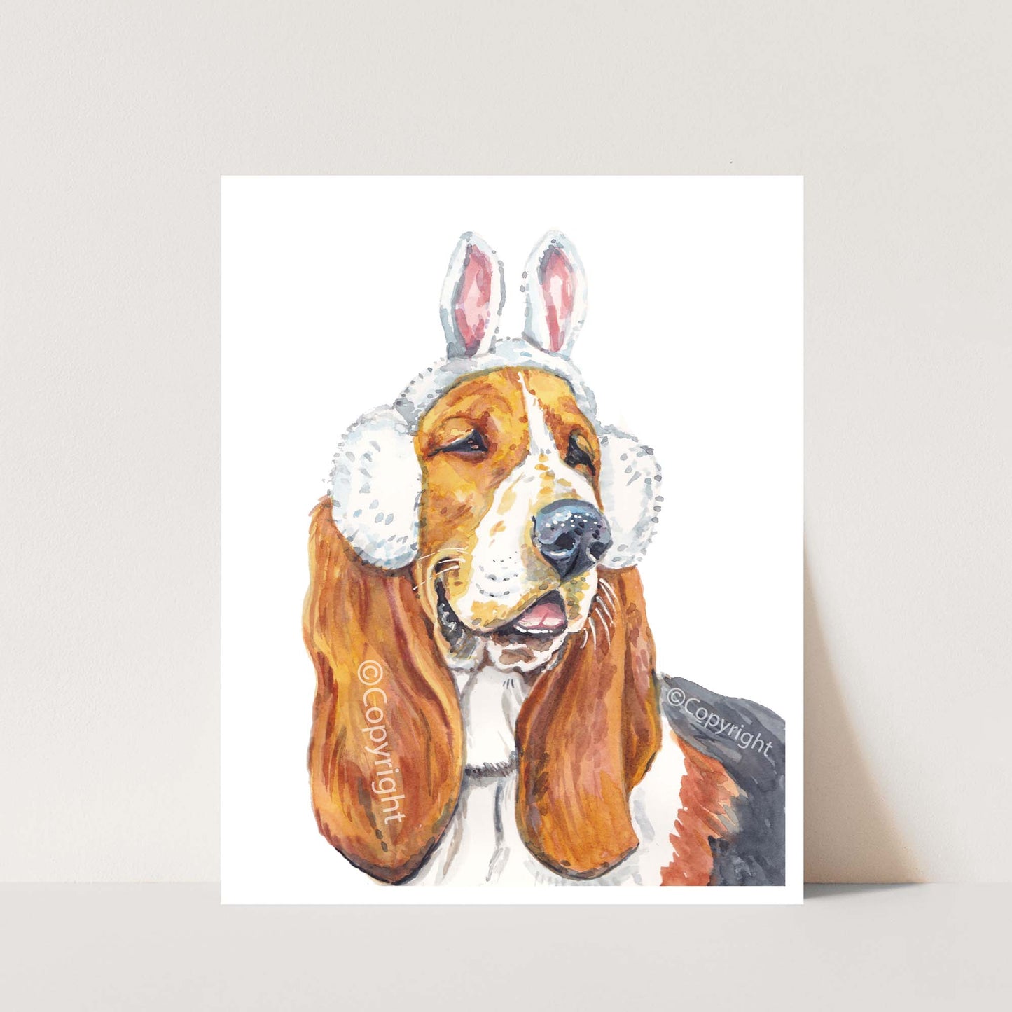 Watercolour painting of a Bassett hound dog wearing a set of ear muffs topped with bunny rabbit ears