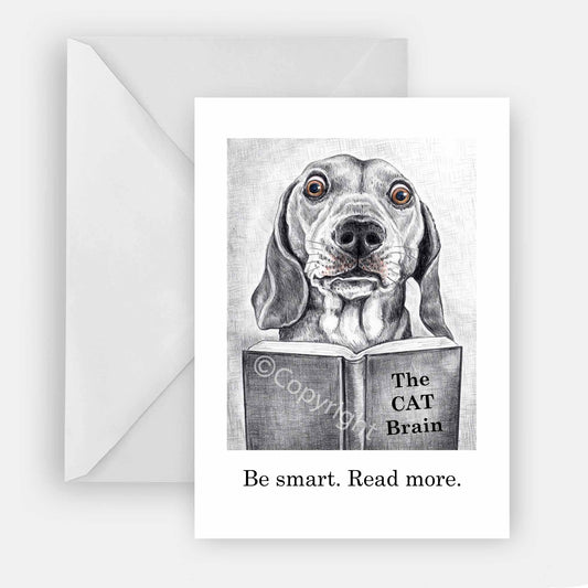 Greeting card featuring a wax pastel drawing of a dachshund dog reading a book about cats. Black and white with a hint of colour. By Deidre Wicks