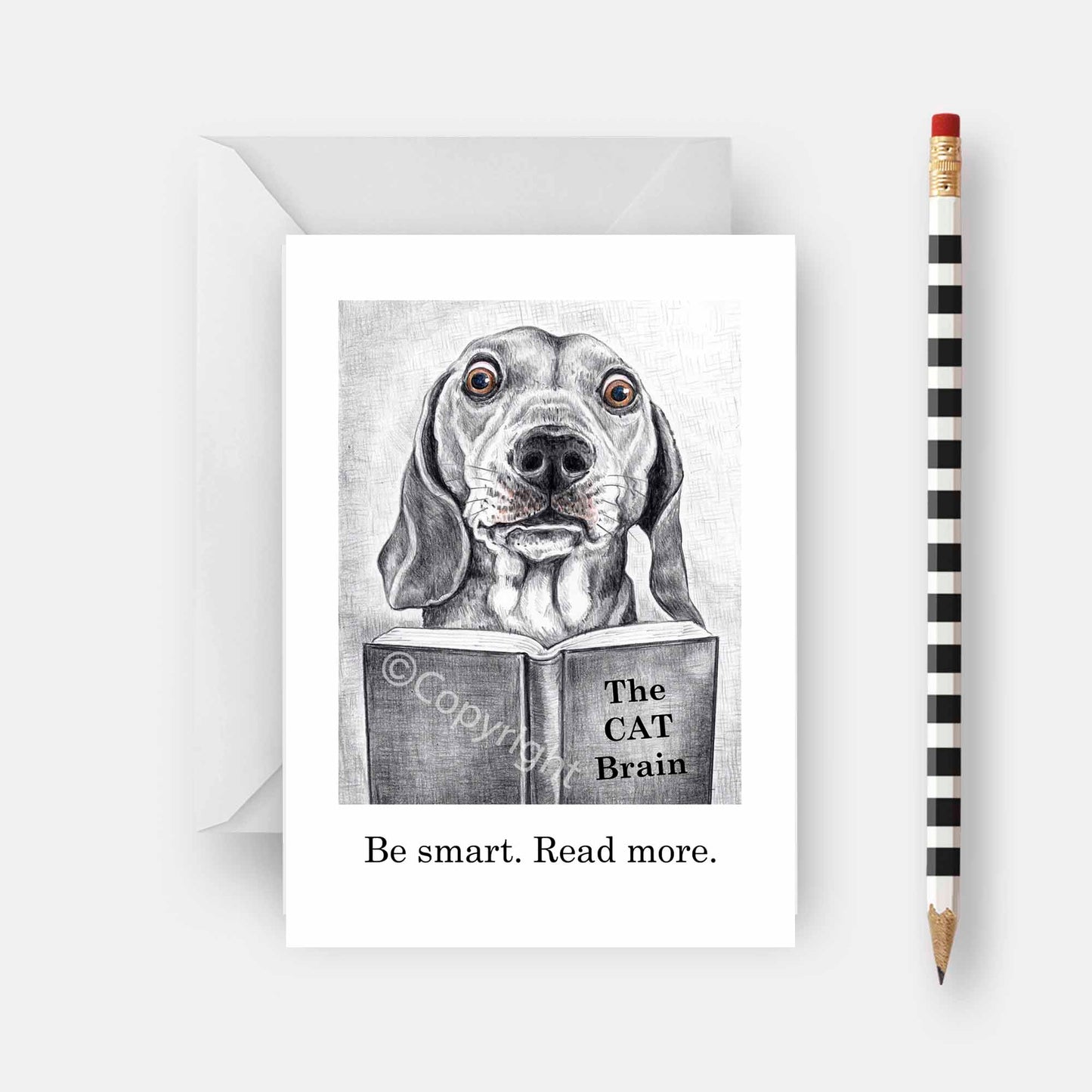 Greeting card featuring a wax pastel drawing of a dachshund dog reading a book about cats. Black and white with a hint of colour. By Deidre Wicks
