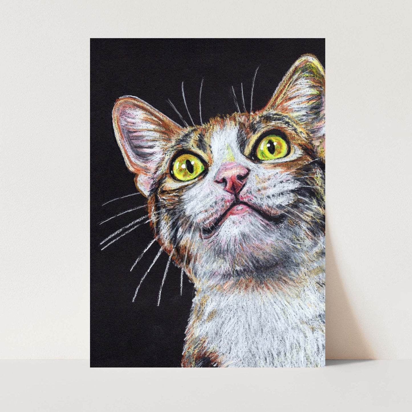 Crayon drawing of an adorable calico cat with big yellow eyes on a black background. Art by Deidre Wicks