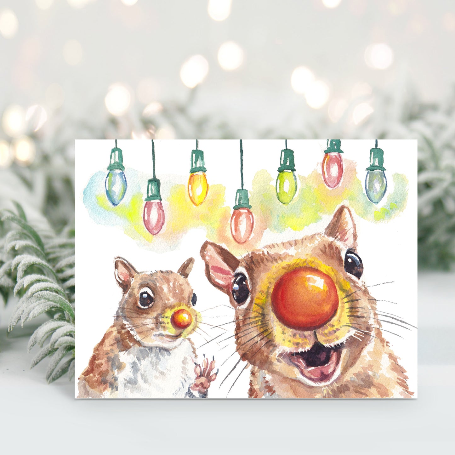 Christmas card featuring a watercolour painting of 2 squirrels wearing Rudolph red noses