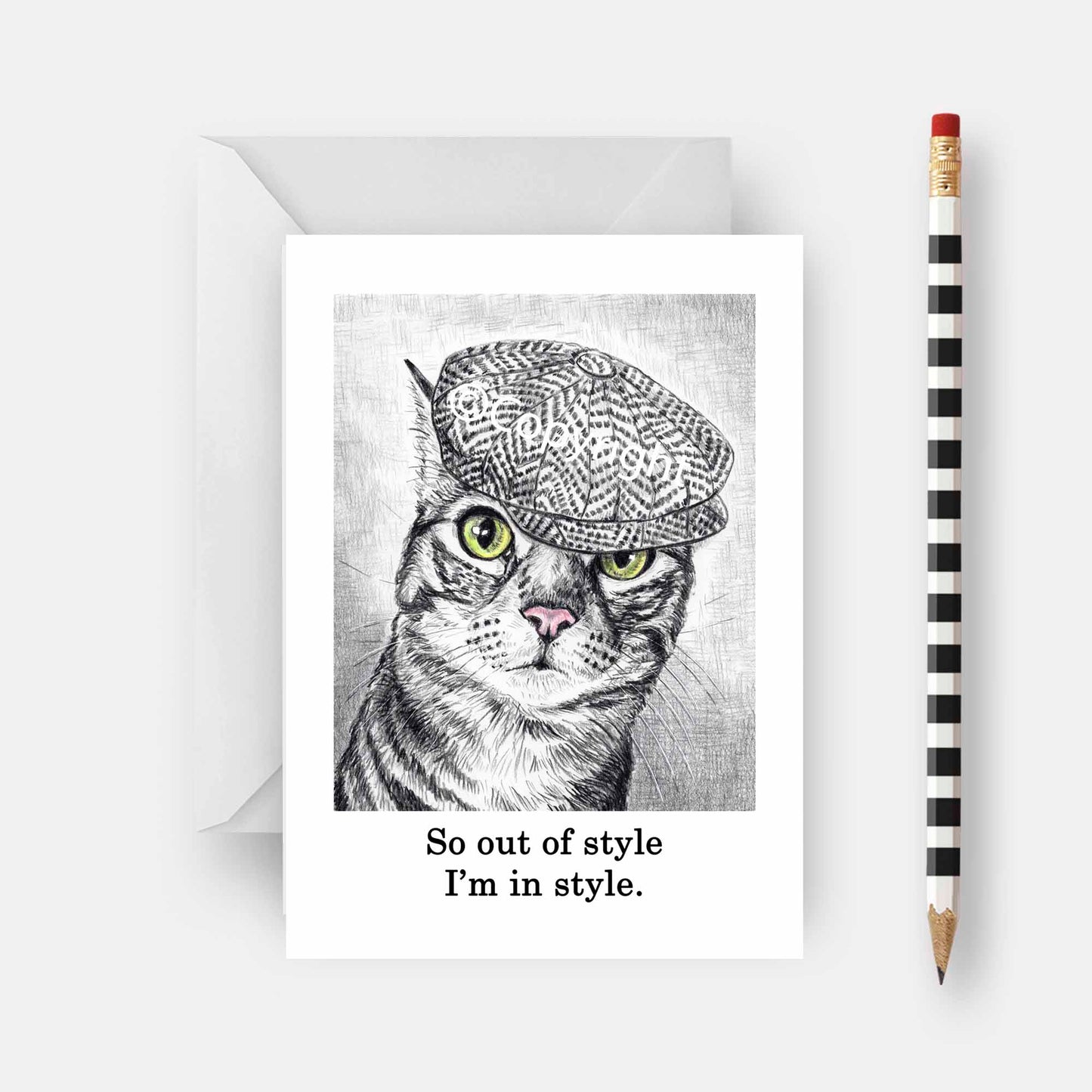Blank greeting card featuring a black and white wax pastel drawing of tabby cat wearing a cap. Art by Deidre Wicks