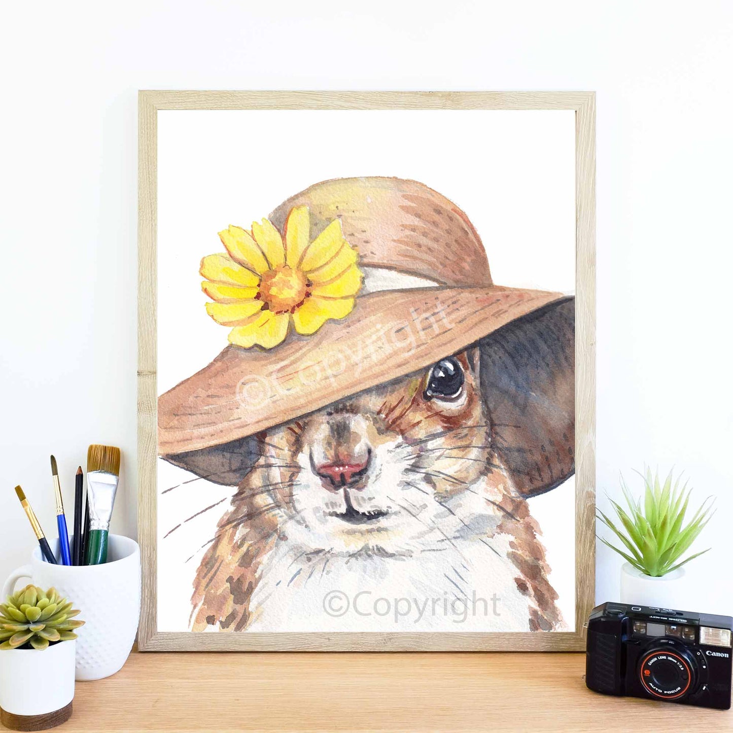 Watercolour painting of a squirrel wearing a floppy Summer hat with a daisy embellishment. Painting by Deidre Wicks