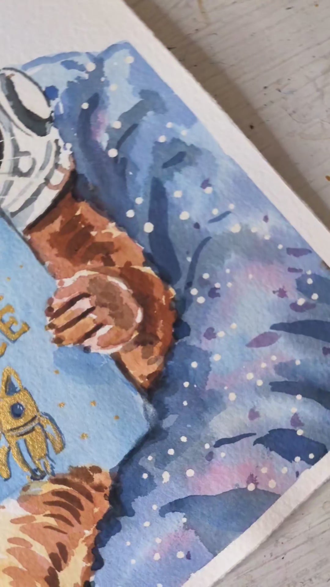 Video of watercolour painting of an otter with a space helmet reading a book about Otter Space