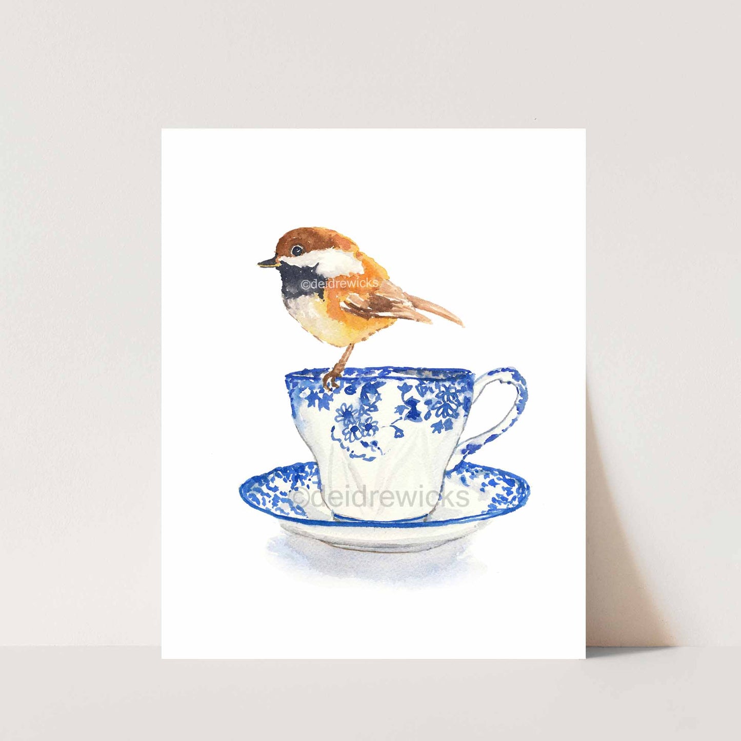 Watercolor of a chestnut backed chickadee sitting on a blue flowered vintage teacup