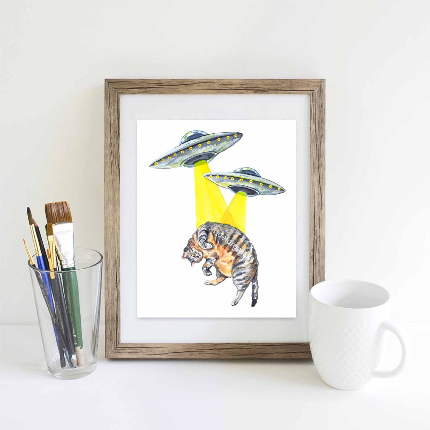 Framed example of a cat and ufo watercolour painting by artist Deidre Wicks