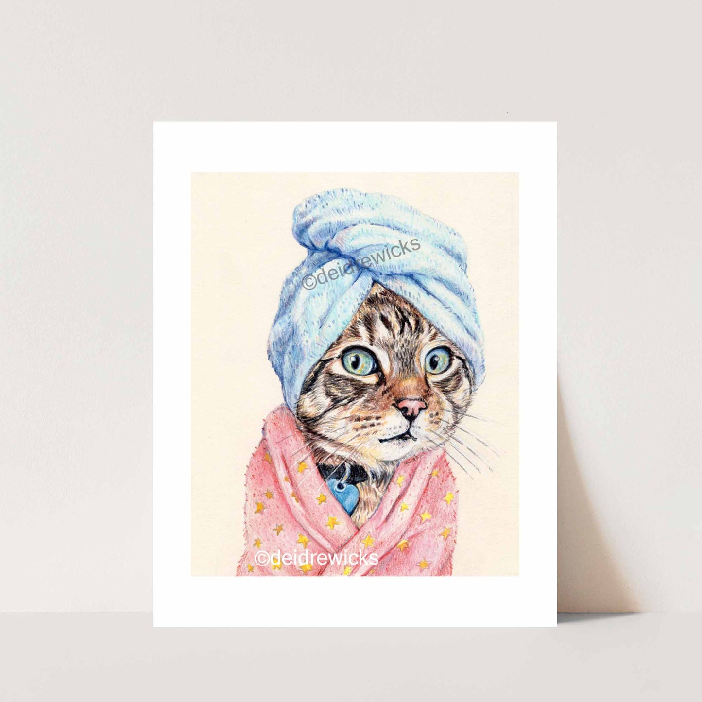 Print of a colored pencil drawing of a tabby cat wearing a pink bathrobe and blue bath towel. Original art by Deidre WIcks