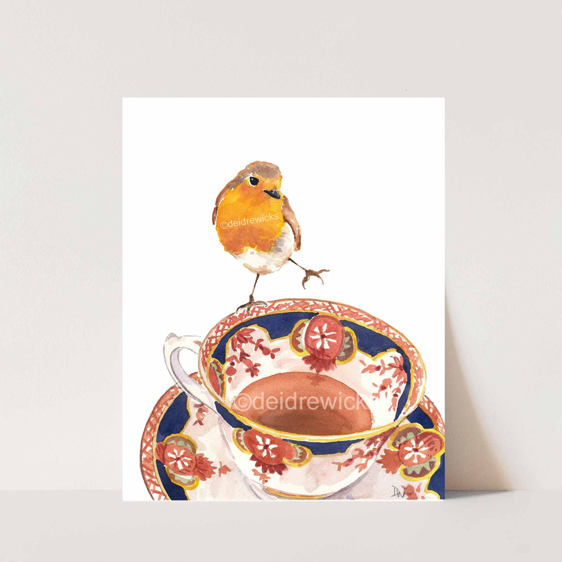 Watercolor painting of a robin bird balanced on the edge of a vintage tea cup